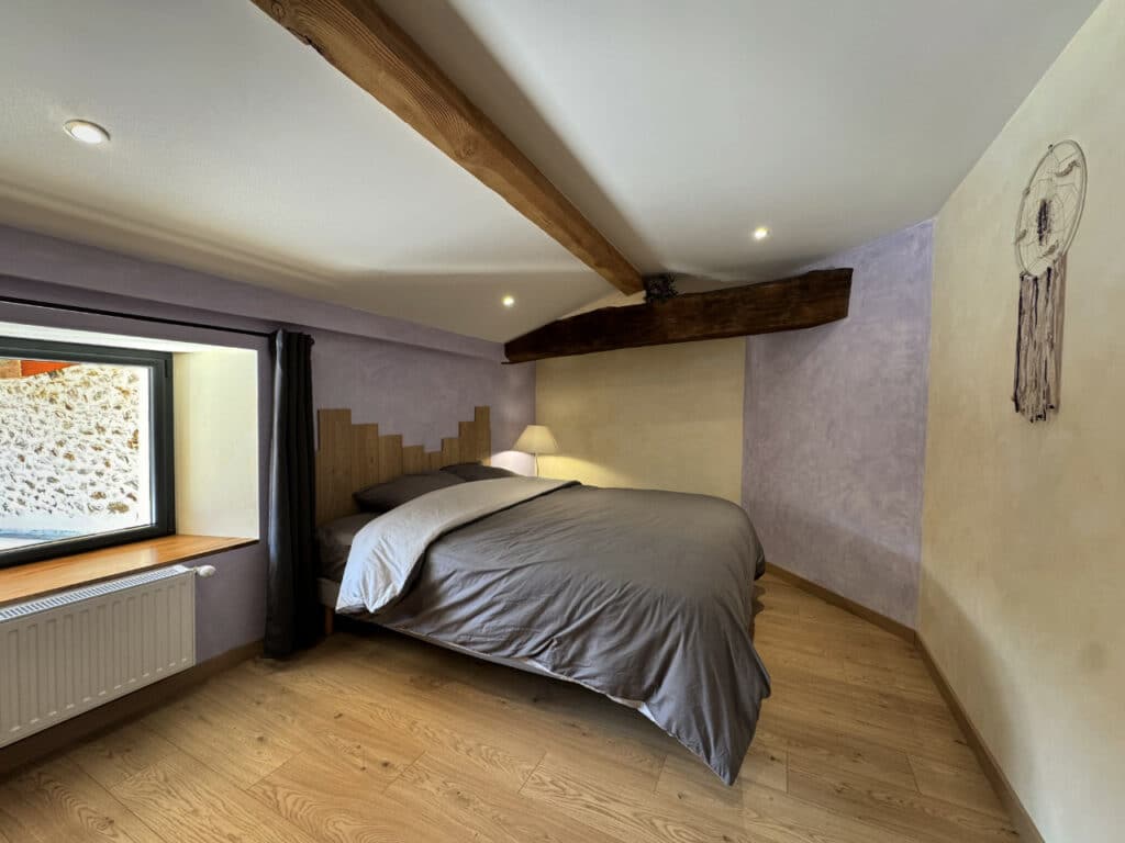 Chambre Côté Cabane avec lit double, mur violet et poutre en bois