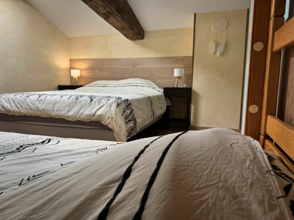 Lit double avec tête de lit en bois et lampes de chevet – chambre Près du Barrage à Doizieux.