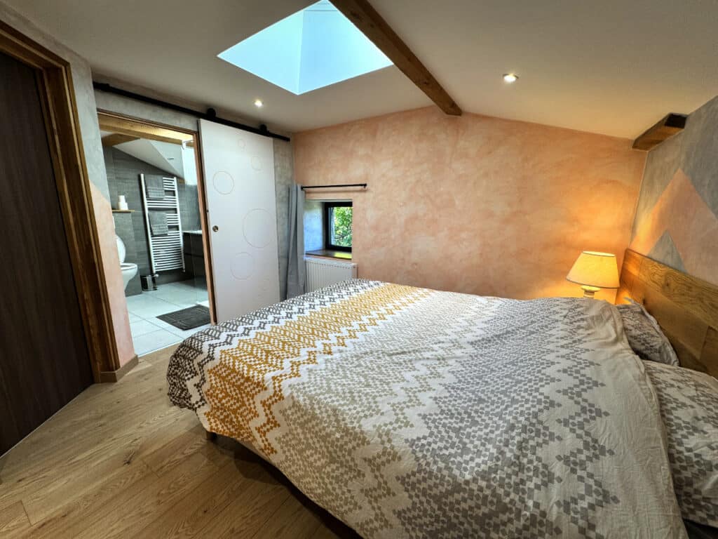 Lit double dans la chambre Tilleul, avec vue sur la salle de bain privative et douche